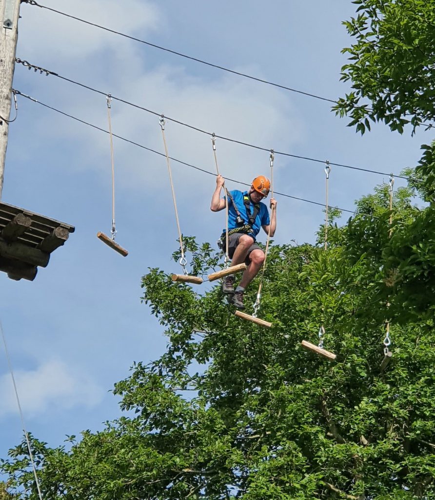 Instructeur klimt op 12 meter hoogte tussen de balkjes bij Klimpark Streekbos